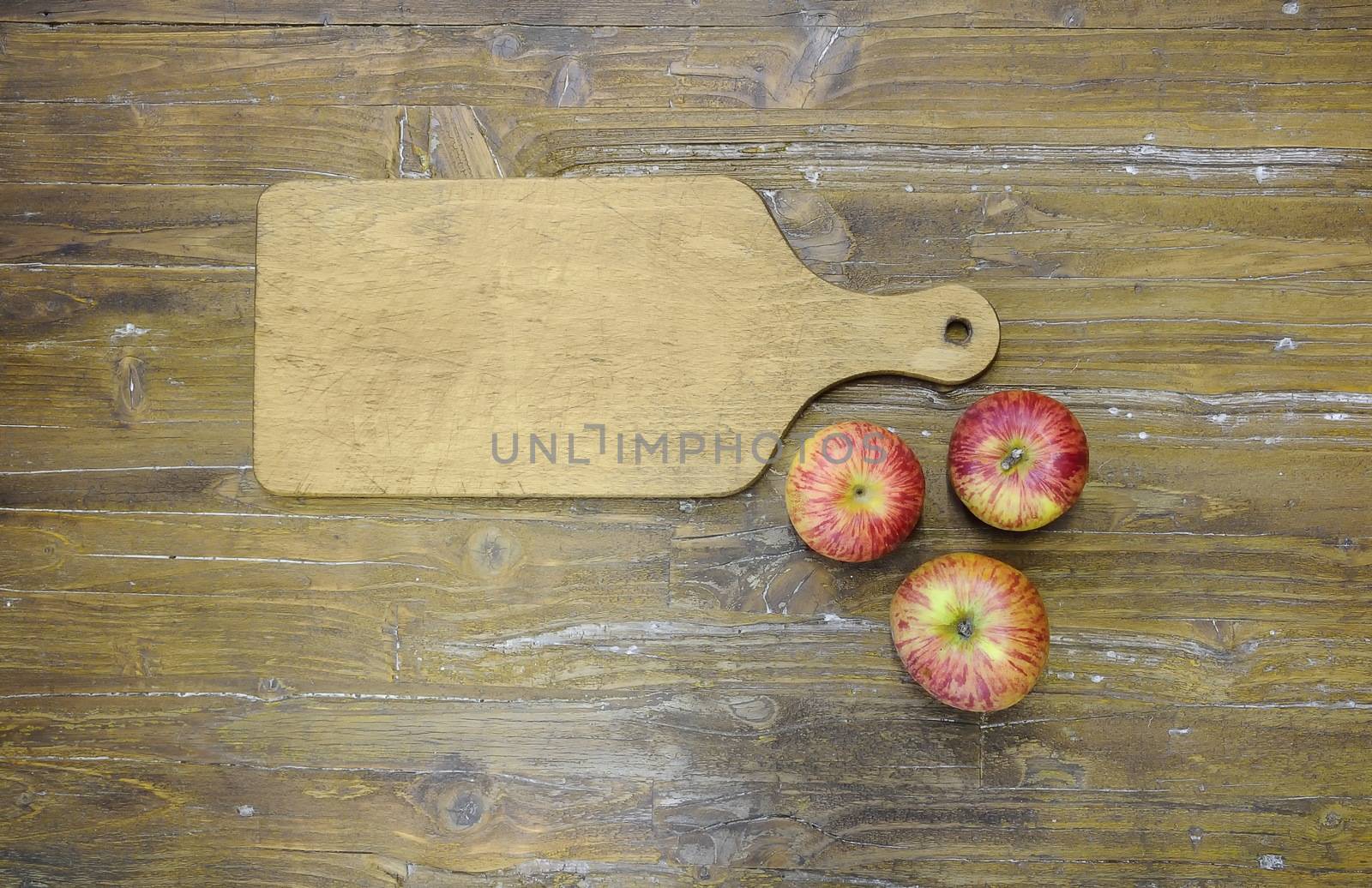 Cutting board in cooking with the three apples.