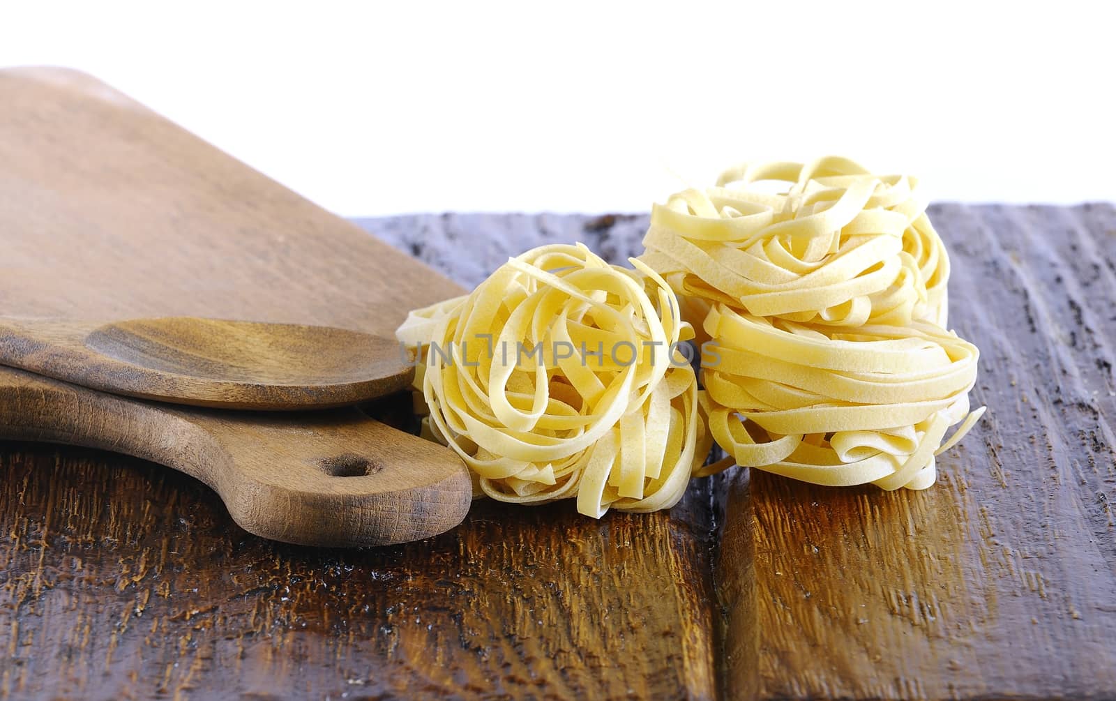 Tagliatelle over kitchen table on white background.