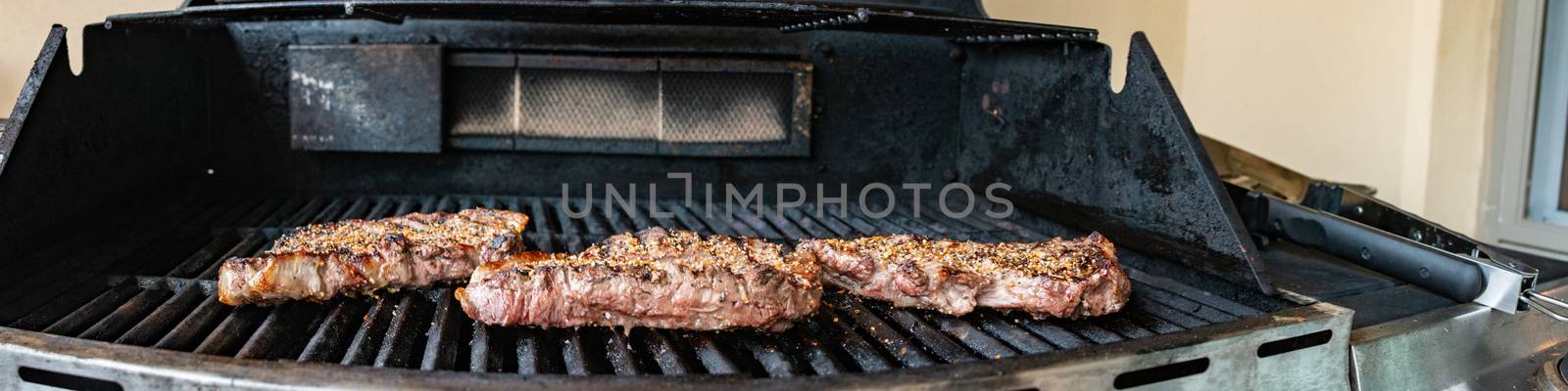 Steaks on the grill. A nice pair of juicy steaks on the grill with grill marks, flames and smoke by mynewturtle1