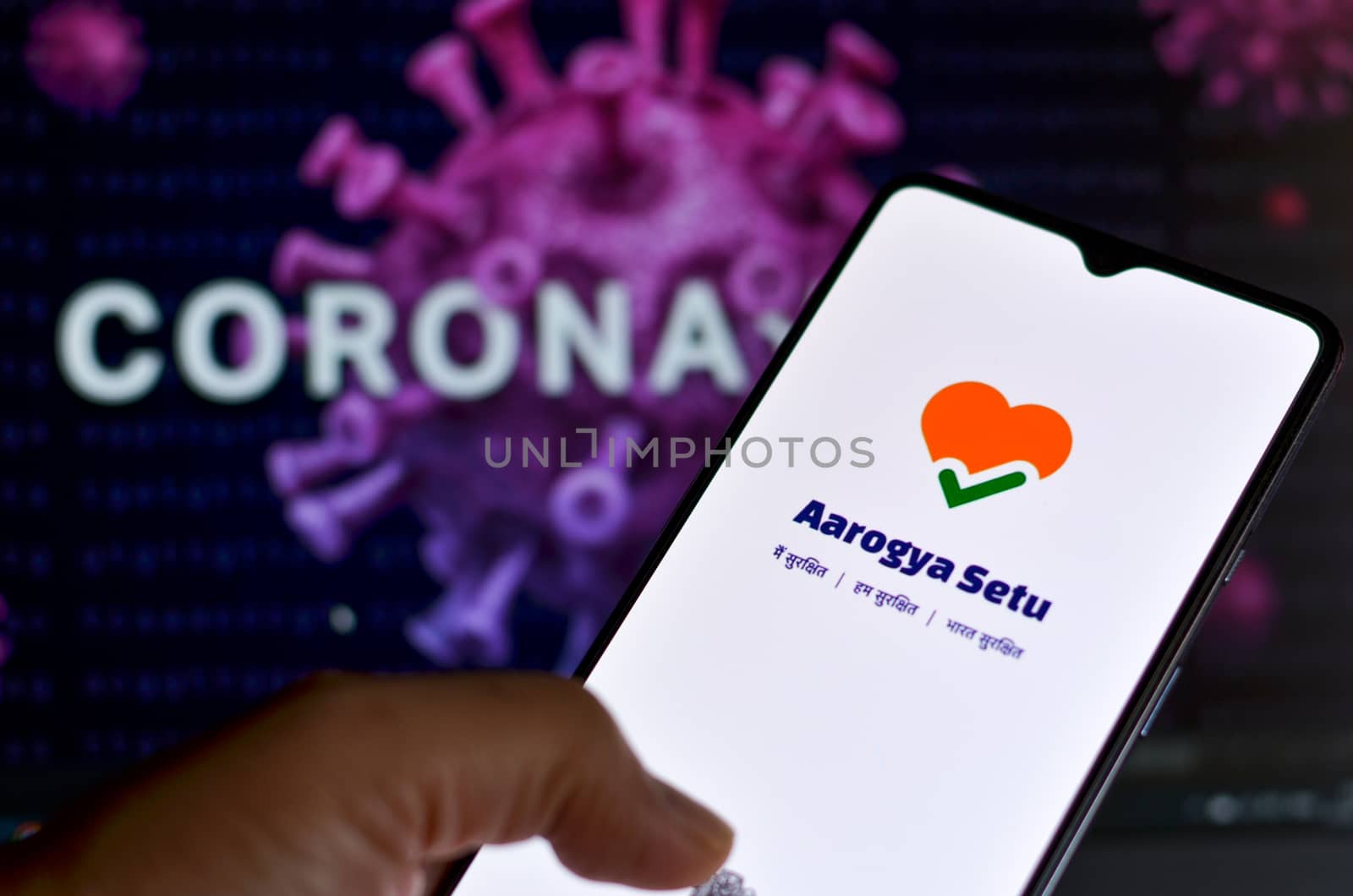 New Delhi, India, 2020. Aarogya Setu app, developed by government of India to track the Covid-19 status, Logged in on a mobile infront of a screen showing microscopic 3D illustration of Corona Virus