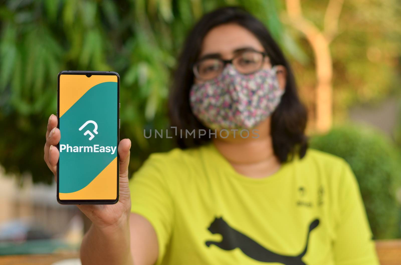 New Delhi, India, 2020. Girl wearing mask with Pharmeasy app on the mobile phone. Only essential services / products are allowed to be delivered during Corona Virus (Covid-19) lockdown