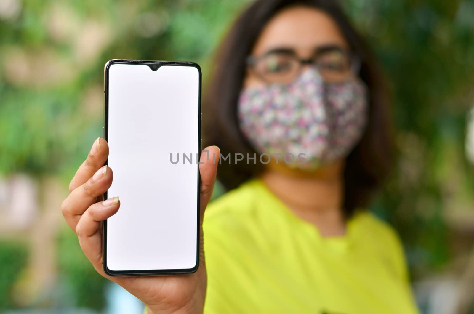Young woman showing her blank mobile phone white screen against yellow background which can be used for copy space for different apps. Concept Happy smartphone user - blank screen for advertising