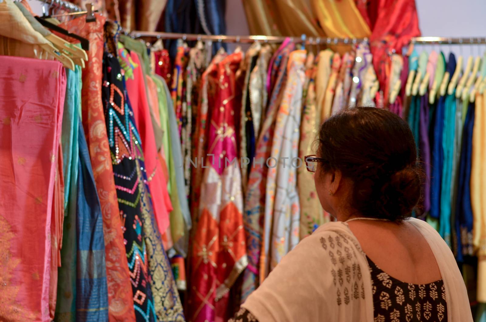 A senior Indian woman wearing glasses checking designer kurta ( Salwar Kamiz) on display at a shop in Dilli Haat or Sarojini nagar market in New Delhi, India