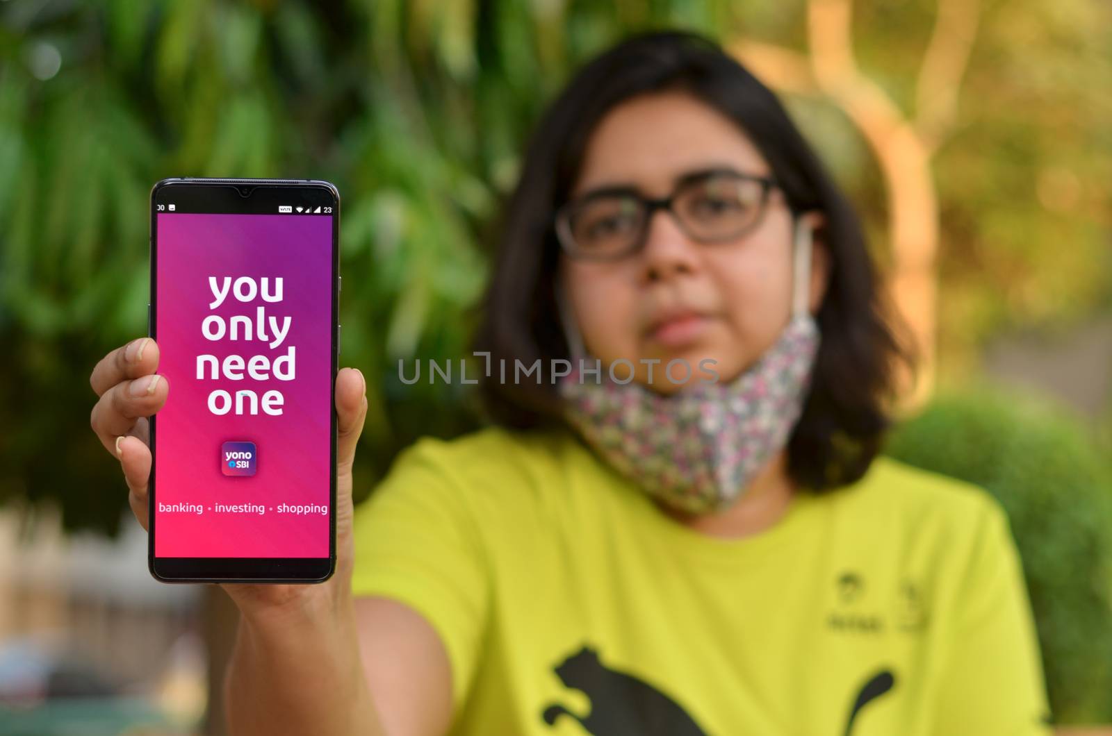 New Delhi, India, 2020. Girl wearing a face mask showing SBI bank app during Corona Virus (Covid-19) disease pandemic. People are encouraged to not visit the bank but do digital banking transactions