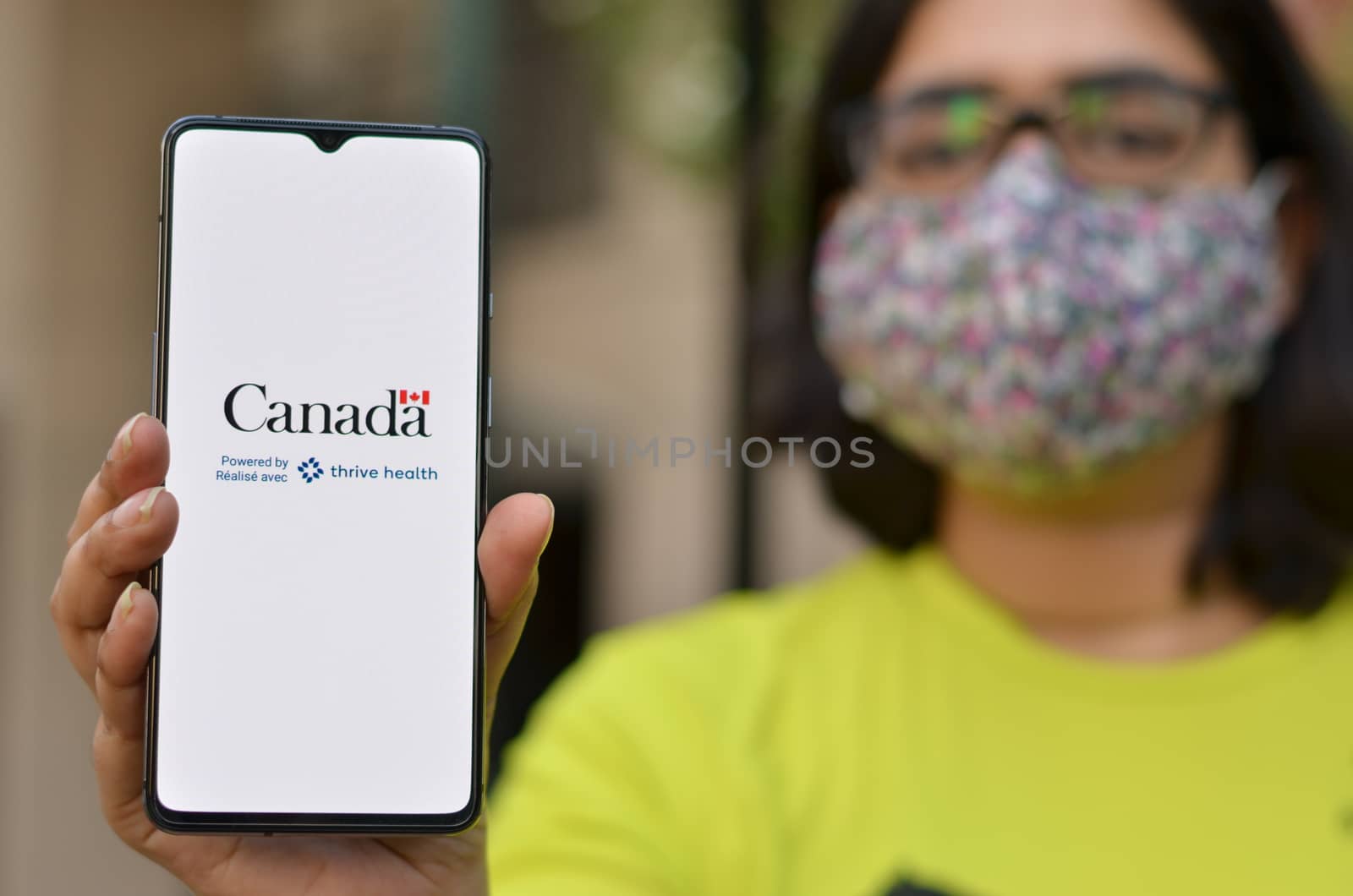 Toronto, Ontario,Canada, 2020. Girl wearing face mask showing Covid-19 app on mobile phone. Health Canada in partnership with Thrive Health has created the Canada COVID-19 app for controlling pandemic