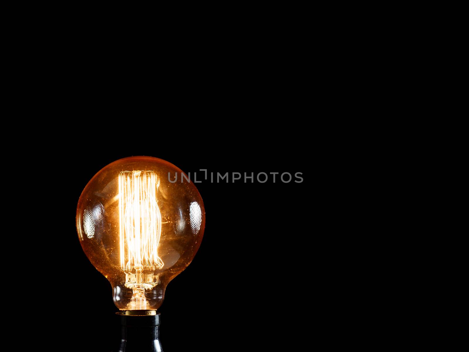 Vintage Edison lamp on black background. Creative idea concept.