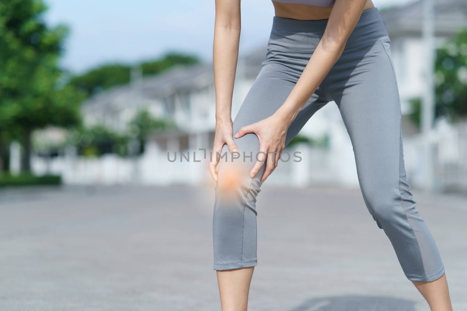 Woman holds her hands to the knee, pain in the knee highlighted in red, medicine, massage concept.