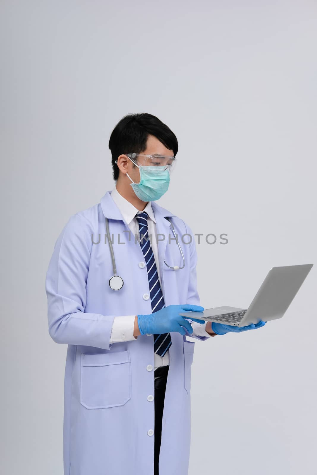 doctor physician practitioner wearing mask with computer & stethoscope on white background. medical professional medicine healthcare concept