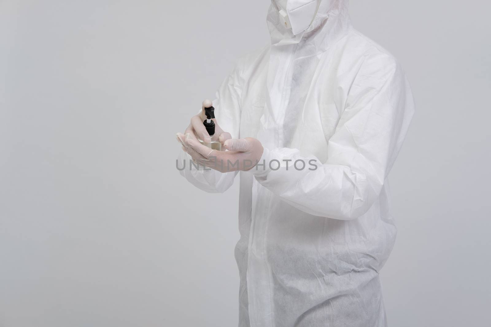 man doctor wearing biological protective uniform suit clothing, mask, gloves washing hand with sanitizer dispenser for sanitizing virus bacteria