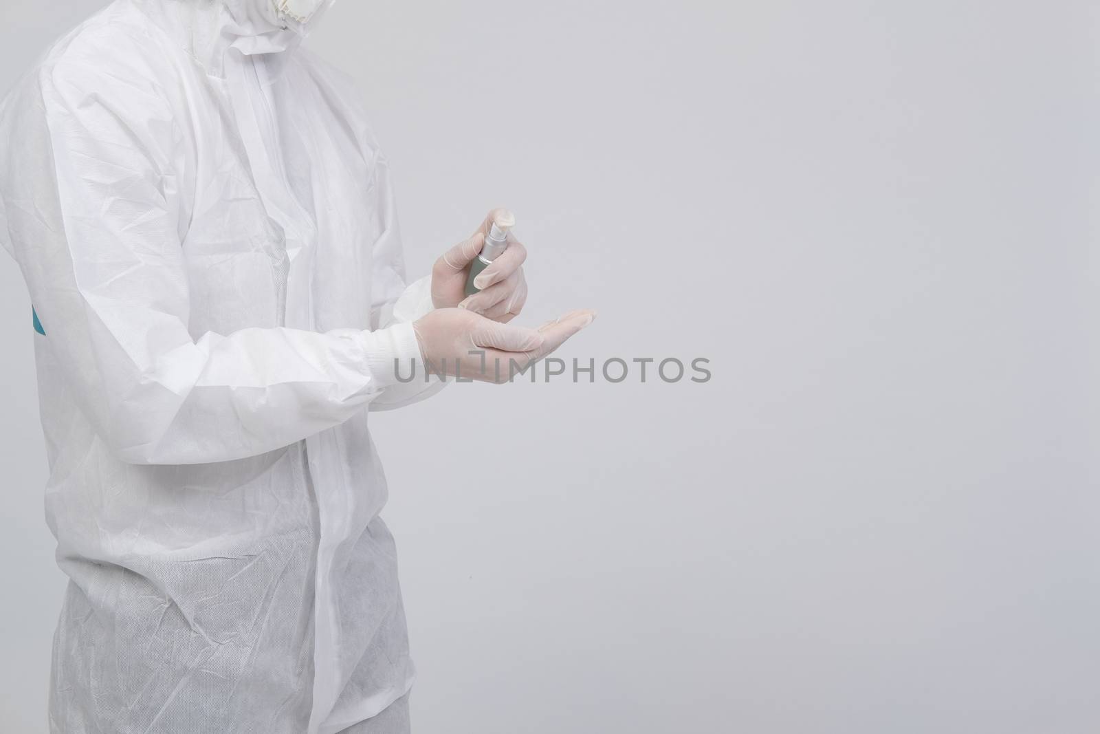 man doctor wearing biological protective uniform suit clothing, mask, gloves with hand alcohol sanitizer dispenser for sanitizing virus bacteria