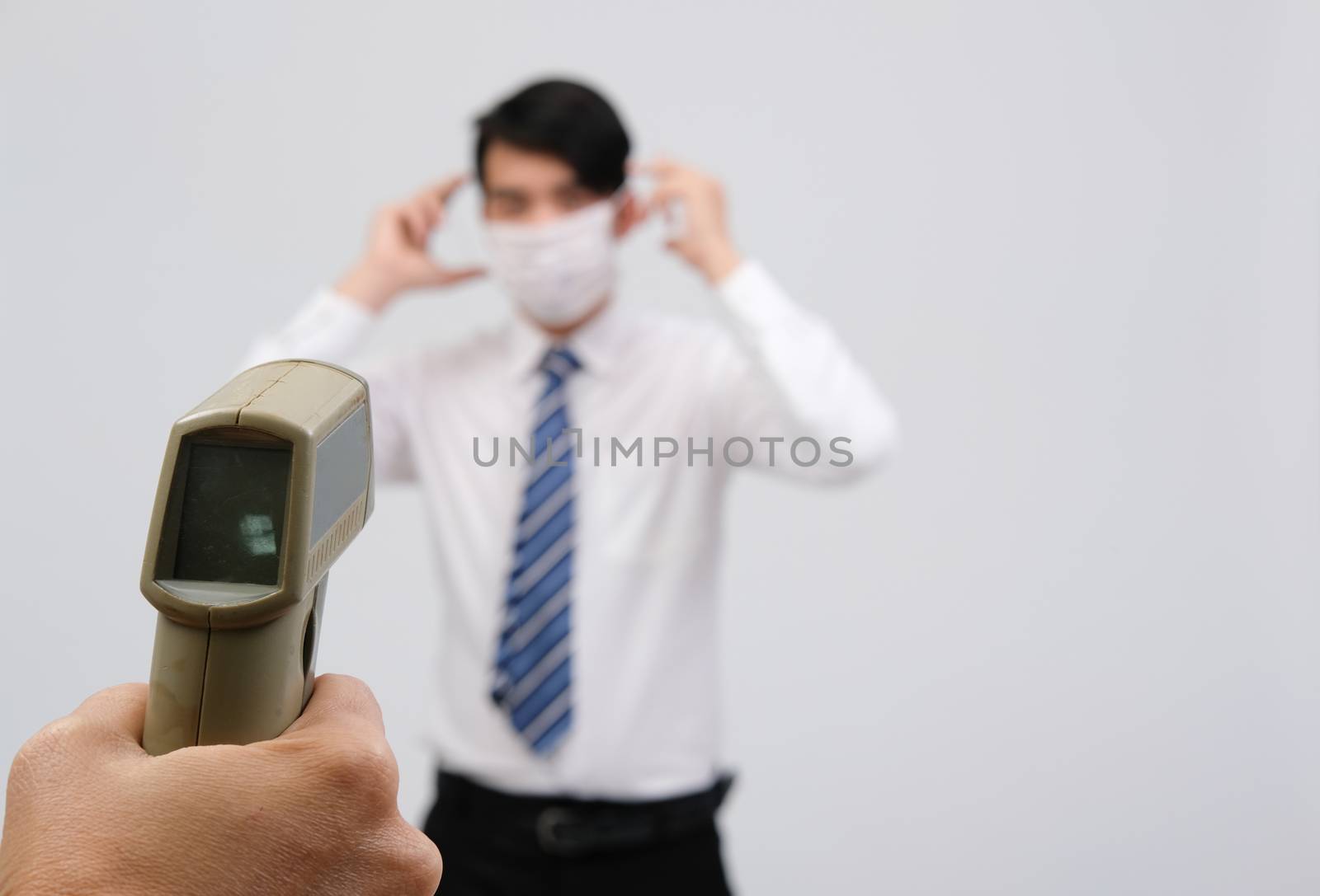 hand measuring body temperature of businessman with infrared forehead thermometer gun