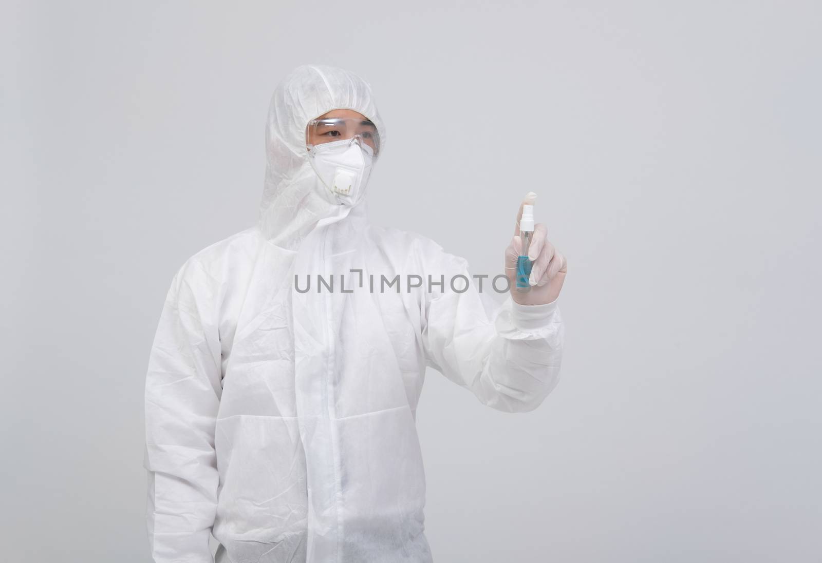 man doctor wearing biological protective uniform suit clothing, mask, gloves with hand alcohol sanitizer dispenser for sanitizing virus bacteria