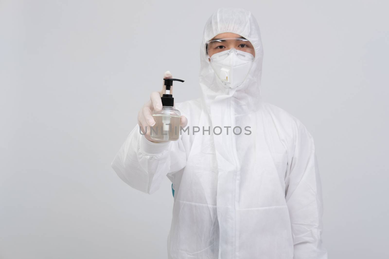 man doctor wearing biological protective uniform suit clothing, mask, gloves with hand sanitizer dispenser for sanitizing virus bacteria