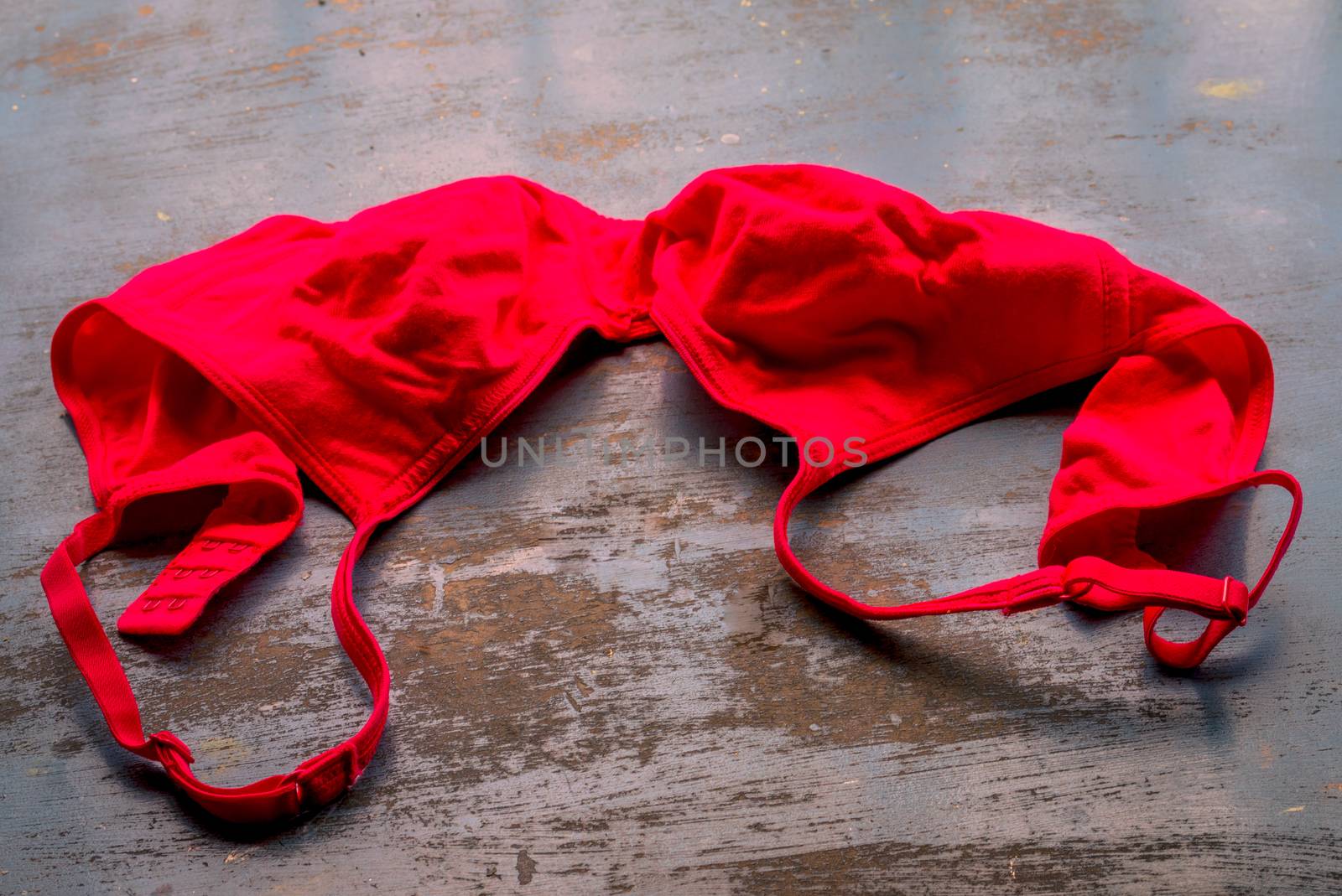 Red bra on rustic metallic floor. Romantic passion female lingerie. Sexy fashion background. Still life.