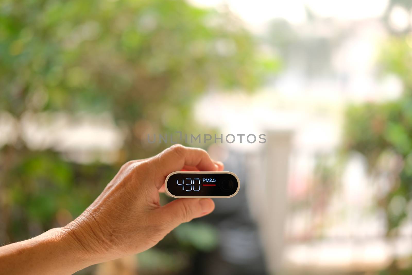 people hand holding pm 2.5 detector for checking air quality. air pollution from fine particle causing bad unhealthy weather