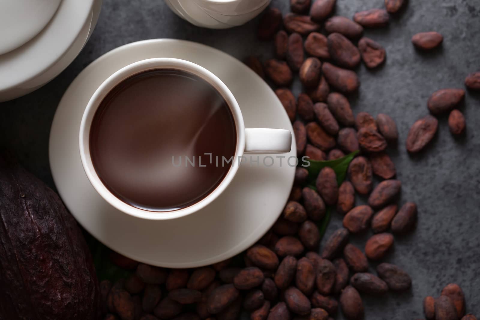 Hot chocolate and Cocoa pod cut exposing cocoa seeds on dark table, top view with copy space.