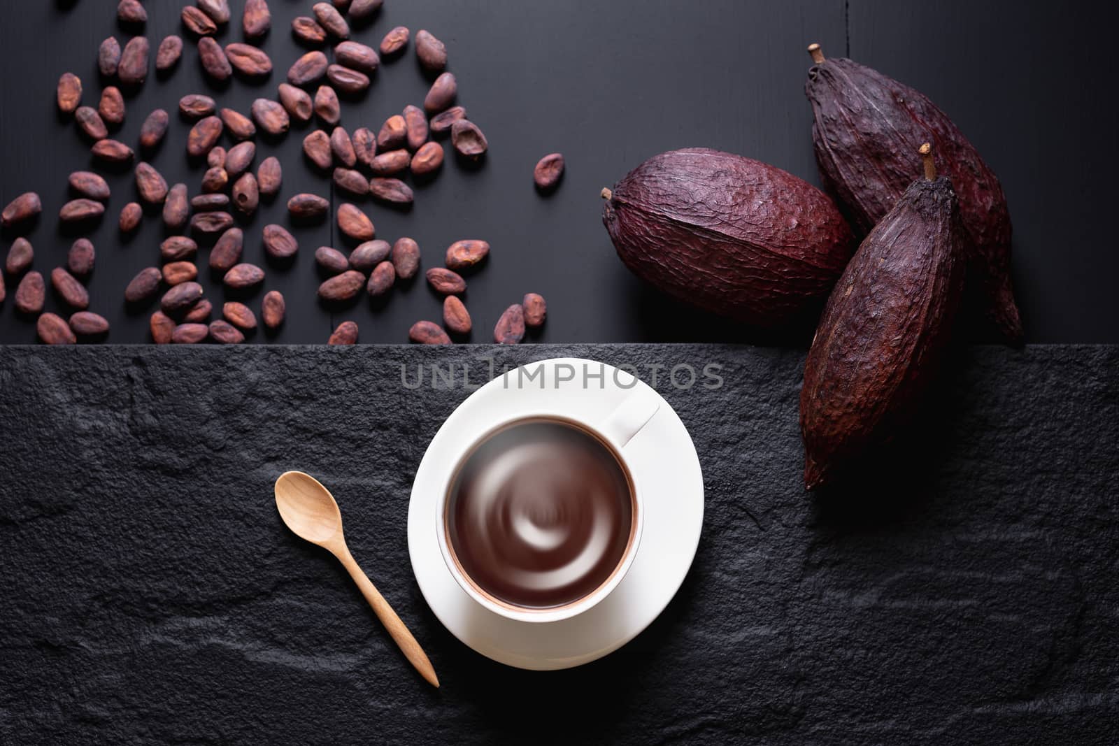 Hot chocolate and Cocoa pod cut exposing cocoa seeds on dark table, top view with copy space.