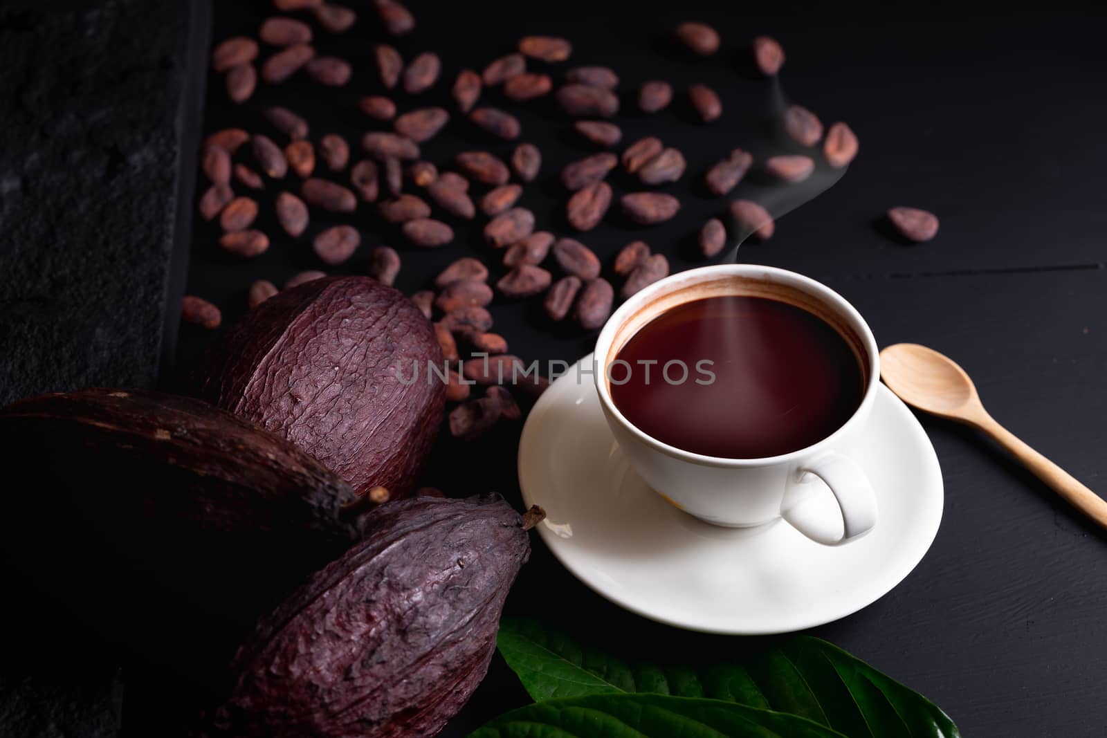 Hot chocolate and Cocoa pod cut exposing cocoa seeds on dark table, top view with copy space.