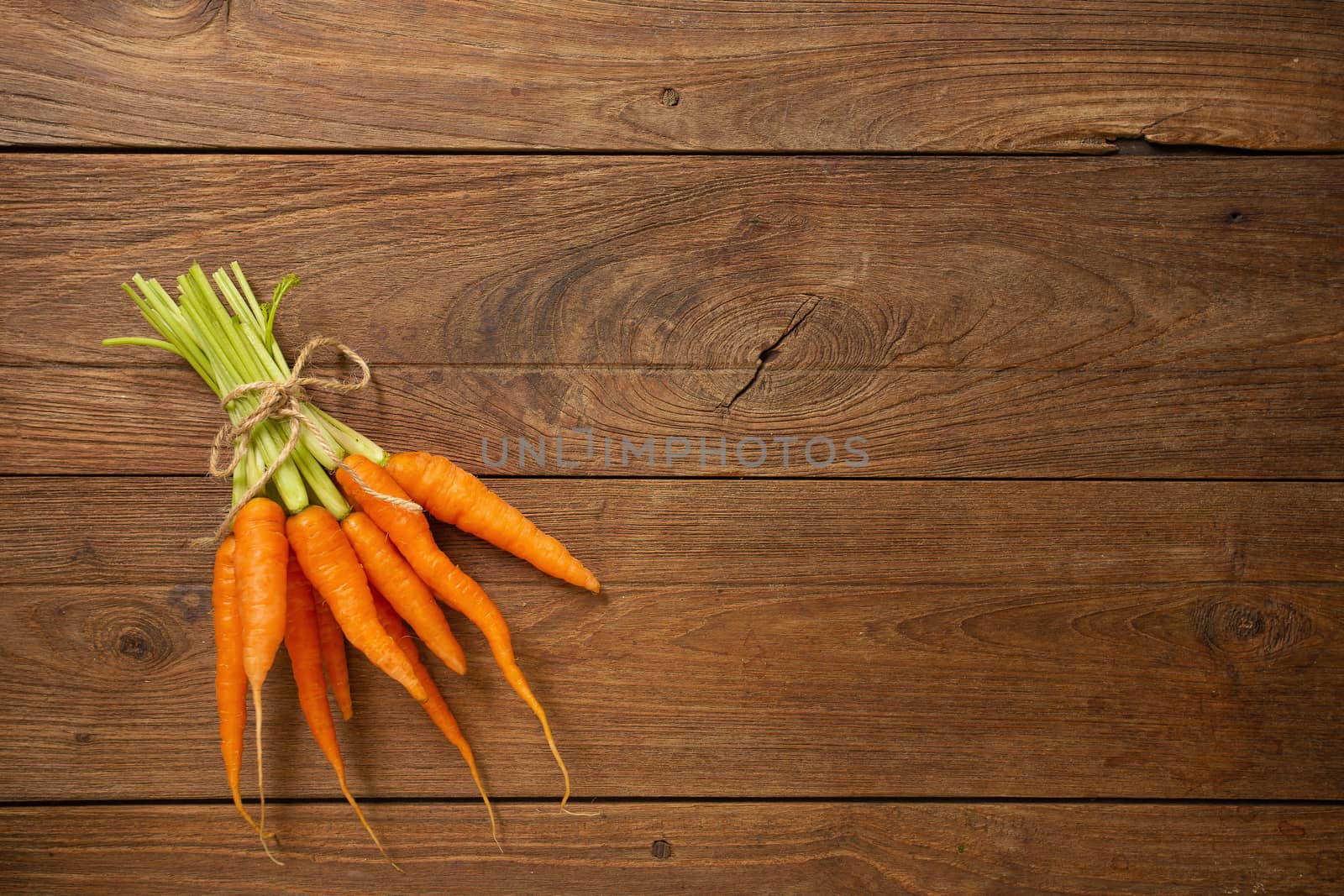 Fresh baby carrots on wooden cutting board and wooden background by kaiskynet