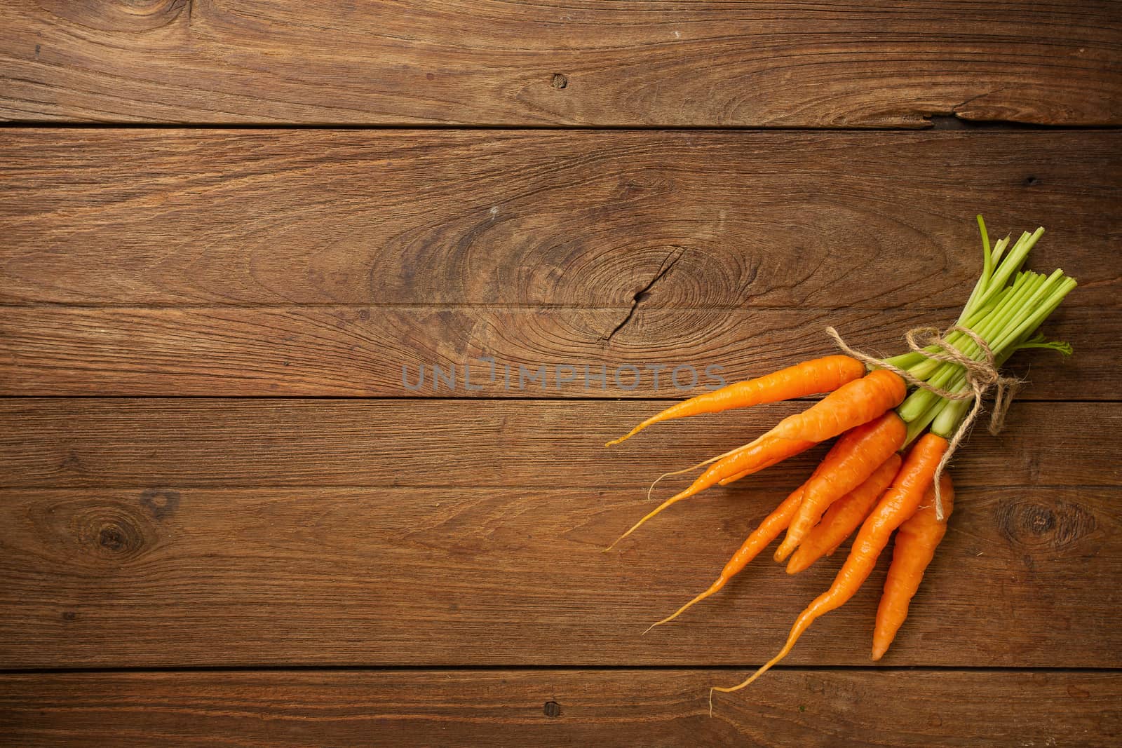 Fresh baby carrots on wooden cutting board and wooden background by kaiskynet