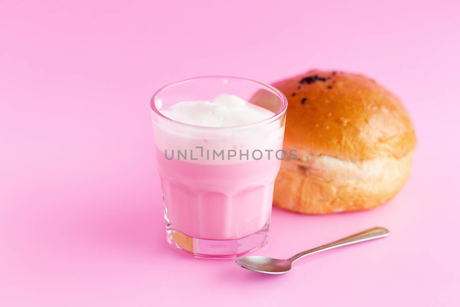 Strawberry milk shake from the glass and bread on pink background.