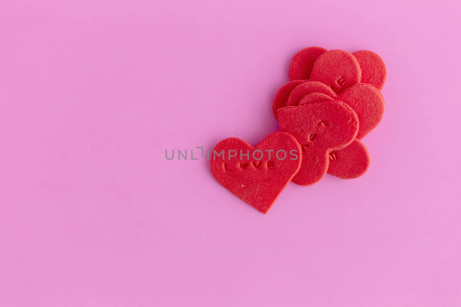 Red heart shaped sugar on pink background.