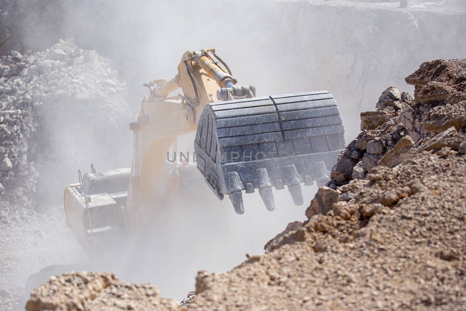 Yellow excavator is filling a dump truck with rocks at coal mine by kaiskynet