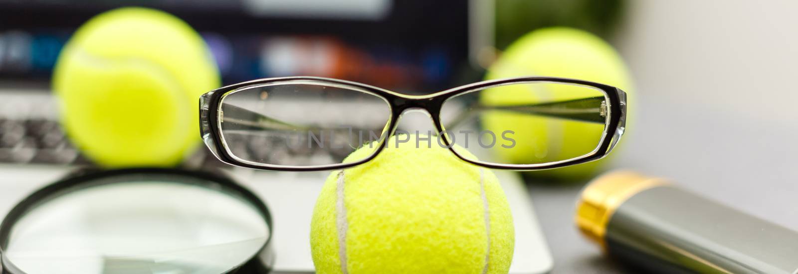 Top view of laptop, Sports Equipment, Tennis ball, glasses on the Sports administration white table.Business concept. by Andelov13