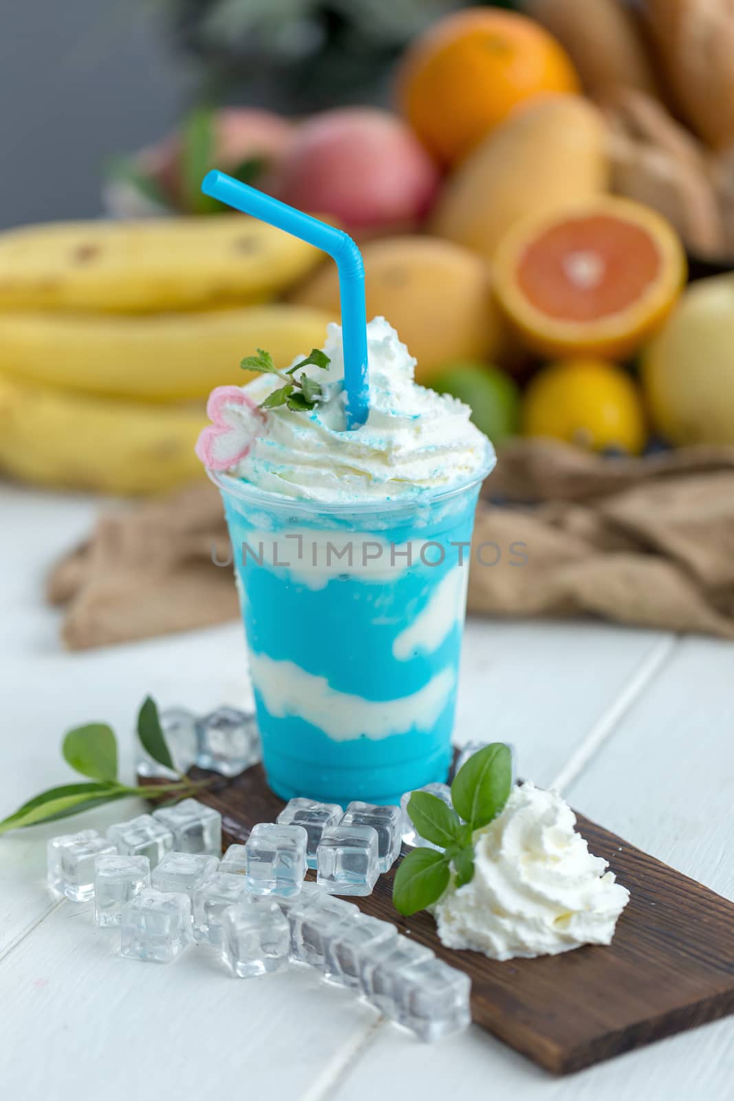 Mint and yoghurt Smoothies on a wooden plate with ice cubes and fruit as background.