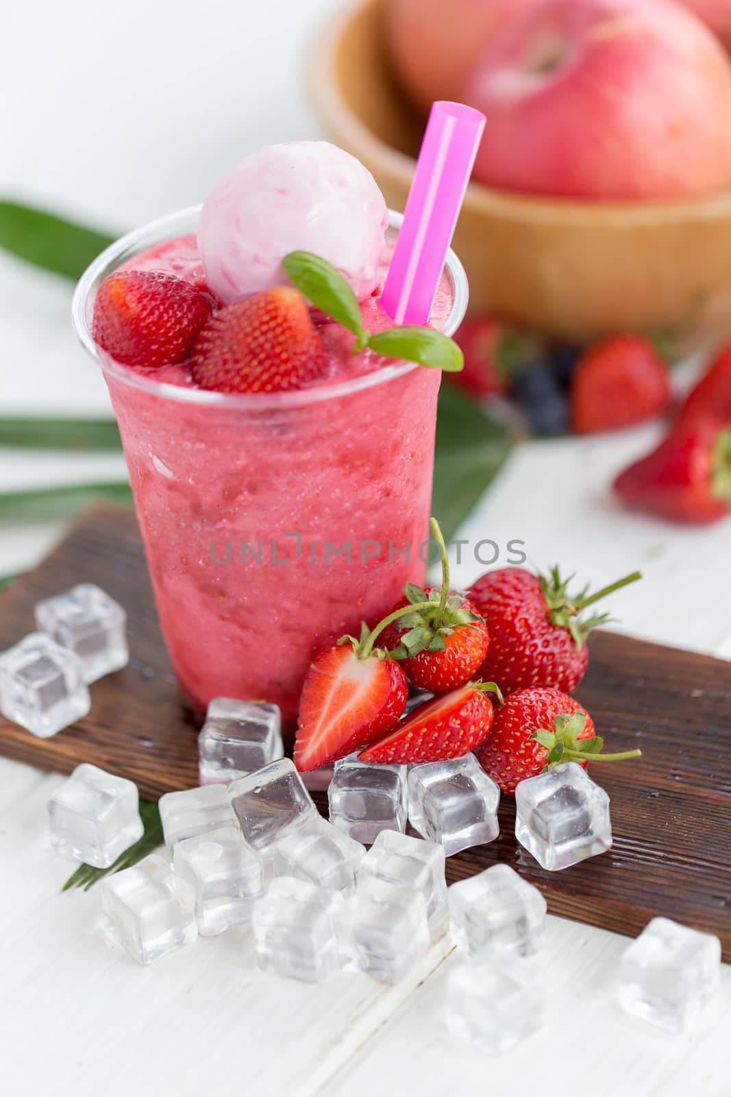 Strawberry smoothie and yogurt ice cream Strawberry on a wooden plate with ice cubes and fruit as background.
