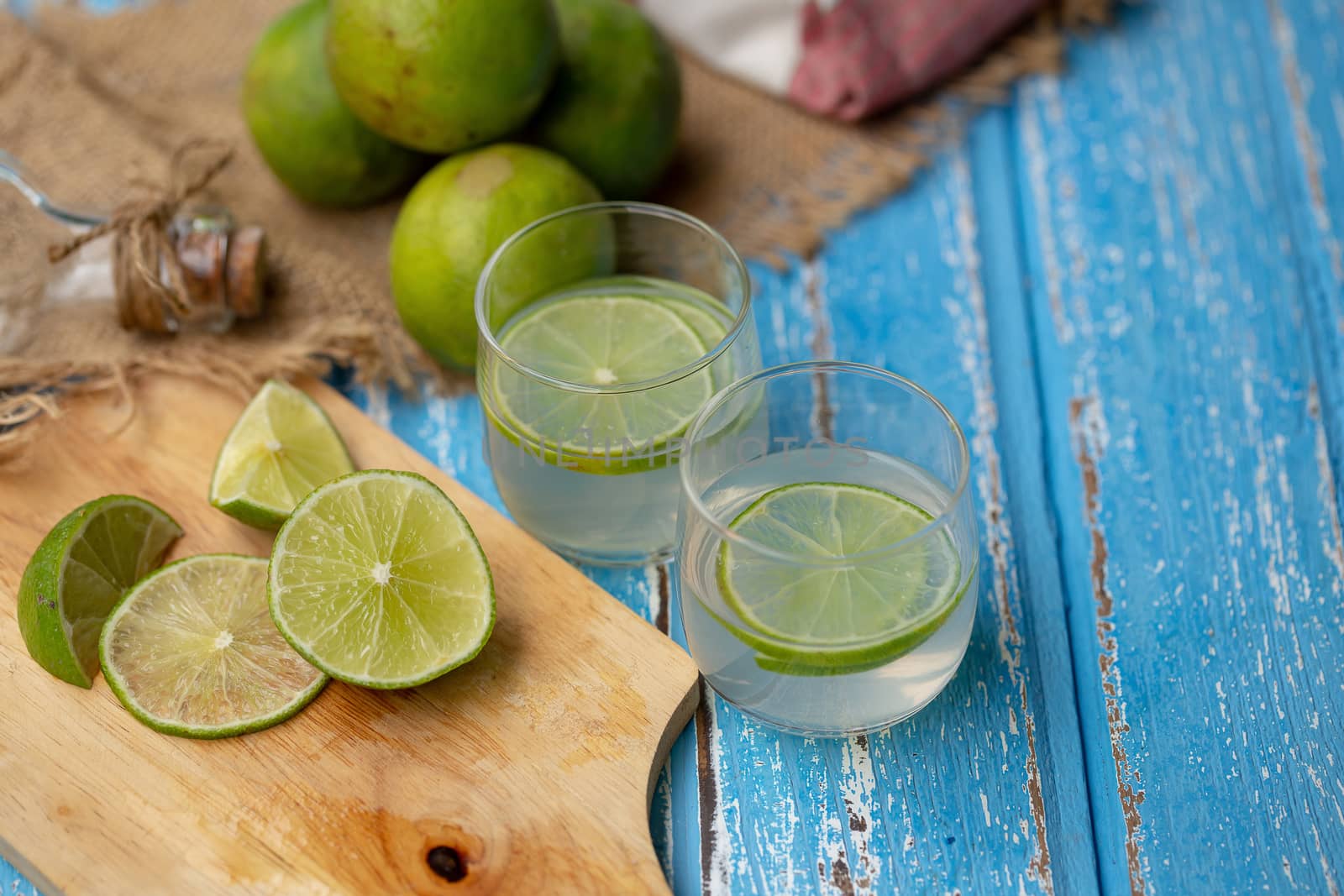 Lime juice and lemon on a blue wooden table.