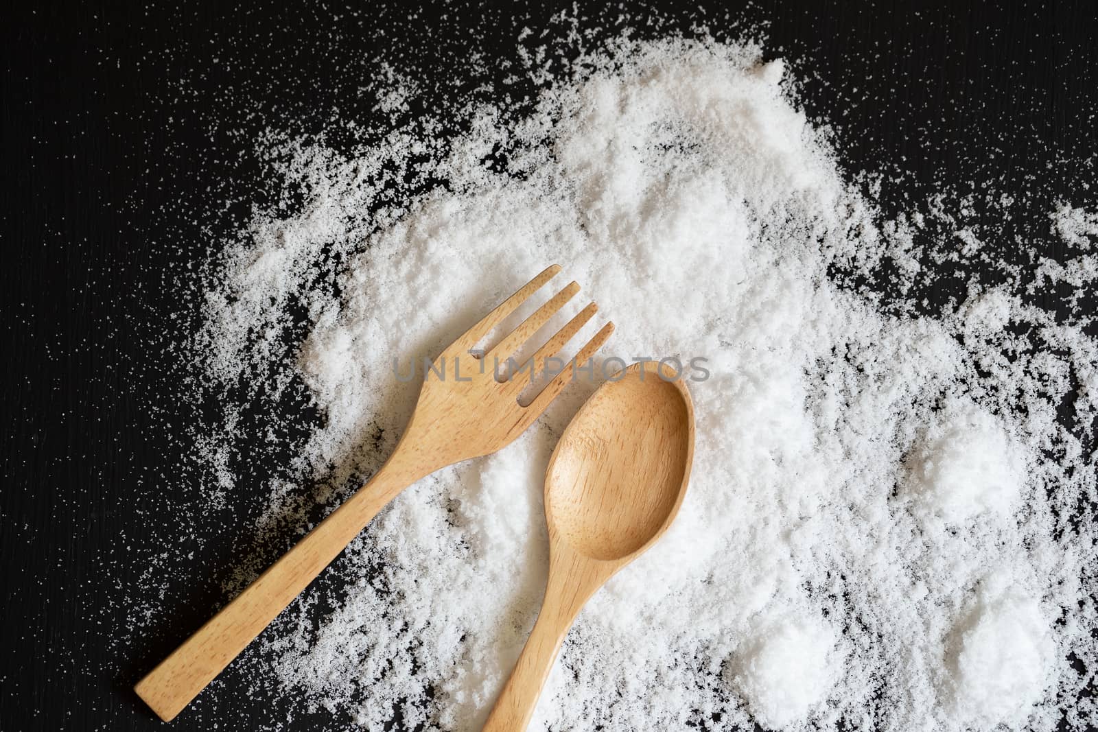 Spoons, forks made of wood on Salt powder and the back wooden background.