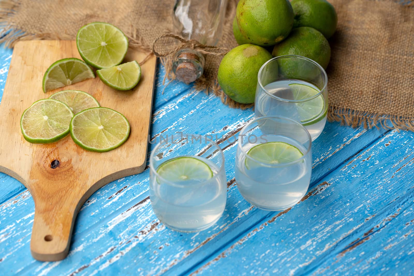 Lime juice and lemon on a blue wooden table.