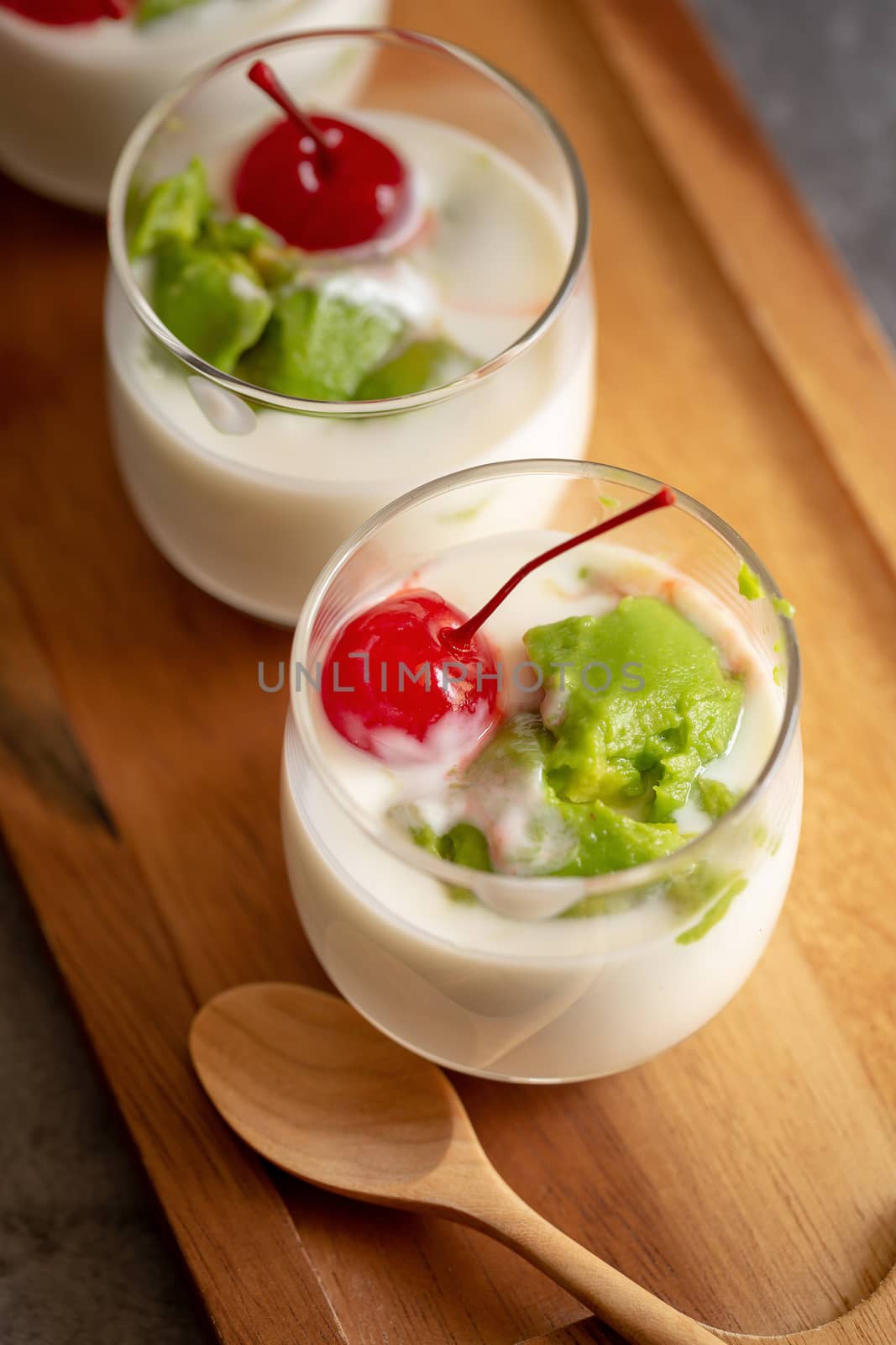 Glass of Cherry and avocado sliced in yogurt on wooden background.