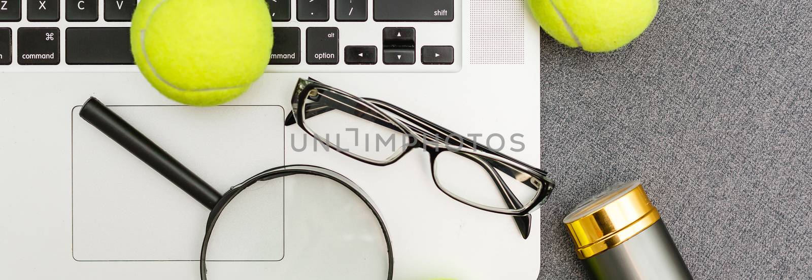 Top view of laptop, Sports Equipment, Tennis ball, Shuttlecock, glasses aon the Sports administration gray table.Business concept. by Andelov13