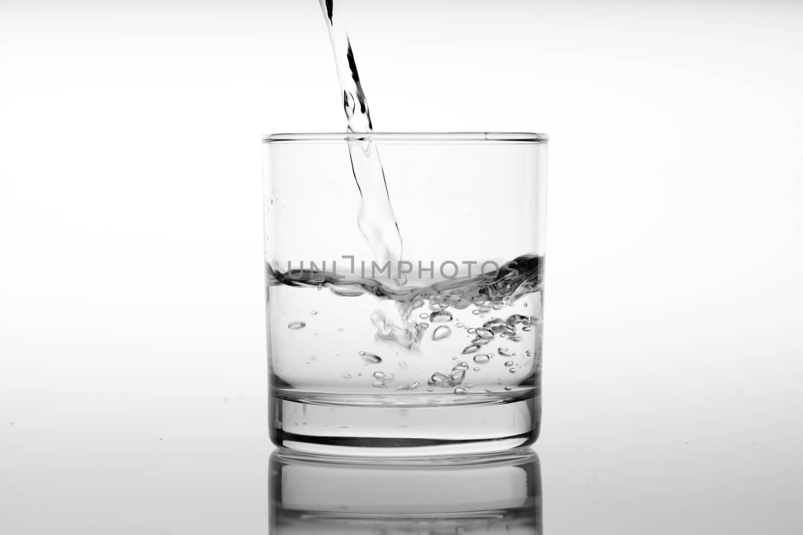 Glass of water with pouring from the bottle, studio shot by Alicephoto