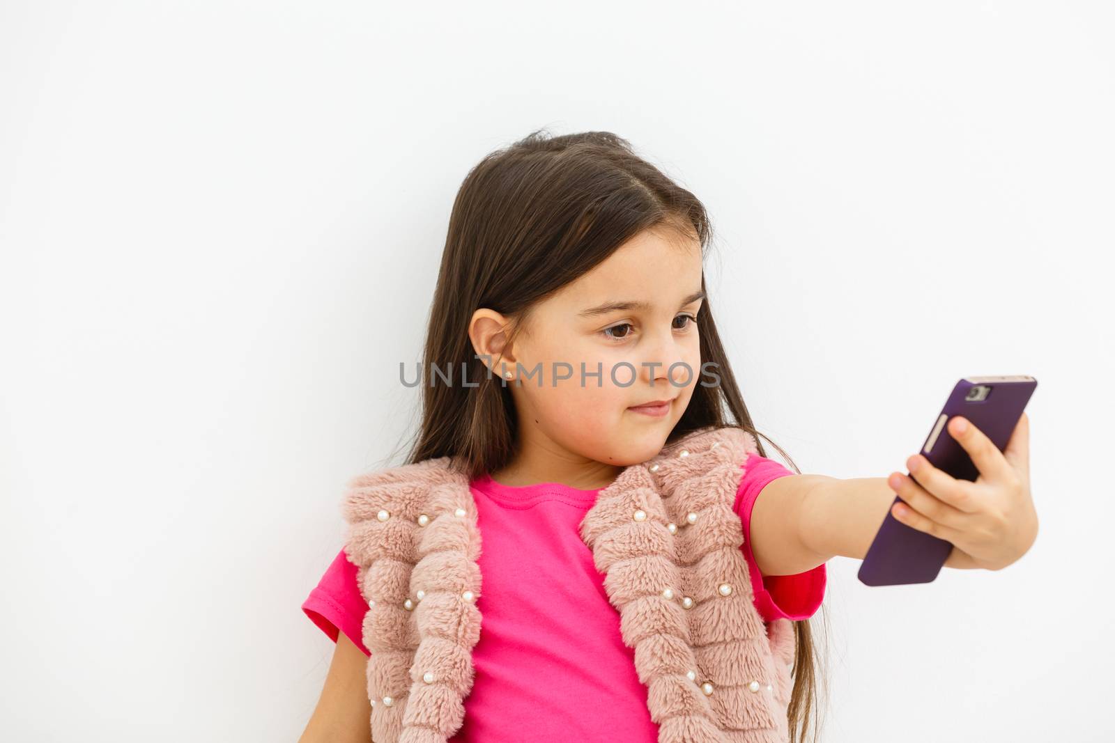 Portrait of little girl taking a selfie isolated over white background by Andelov13