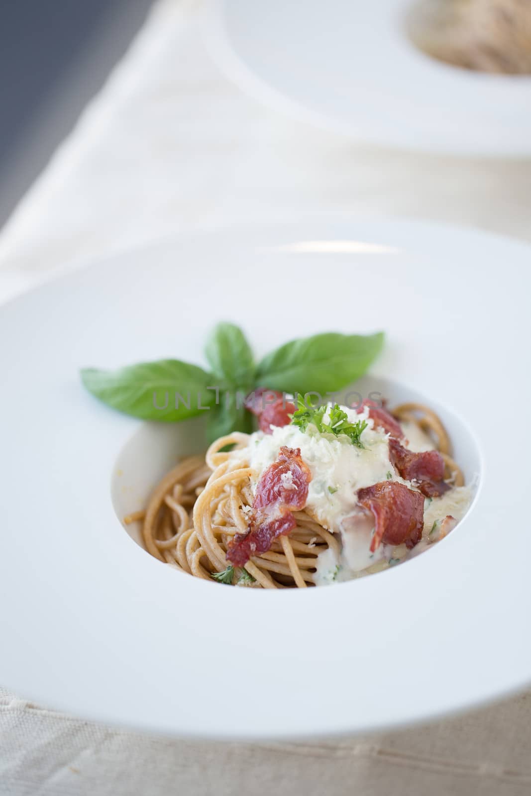 Spaghetti carbonara with bacon and cheese on white plate by kaiskynet