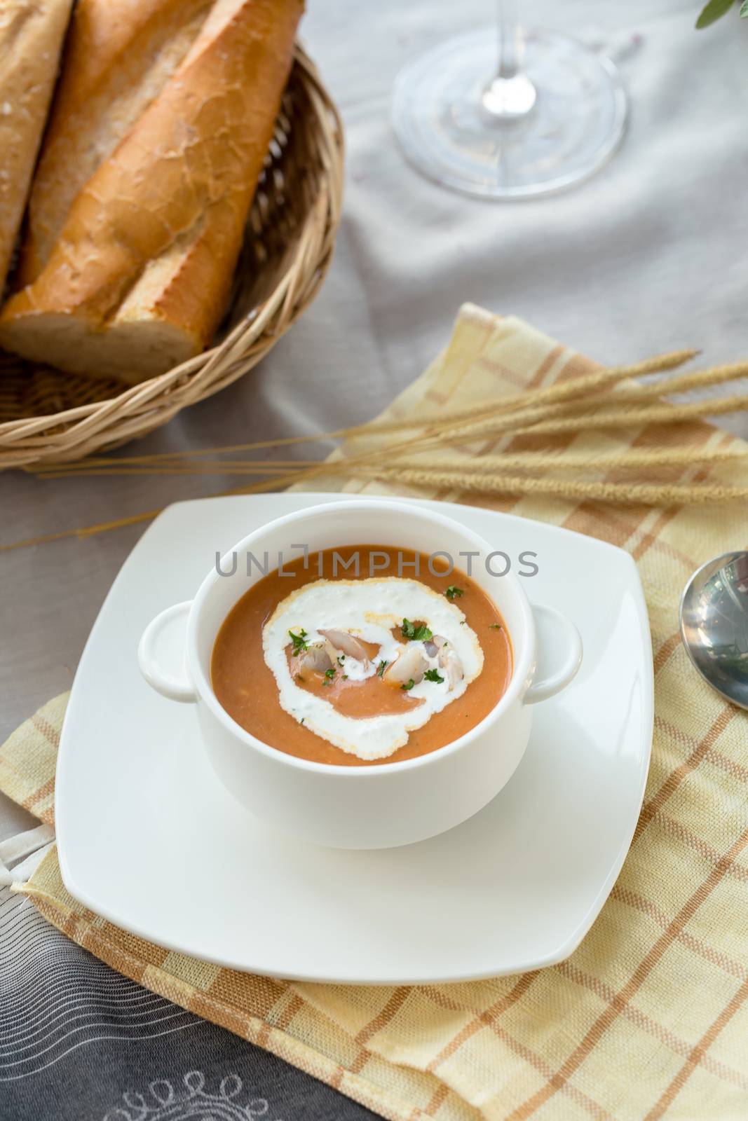 Vegetable cream soup with shrimps and croutons in white bowl close up.