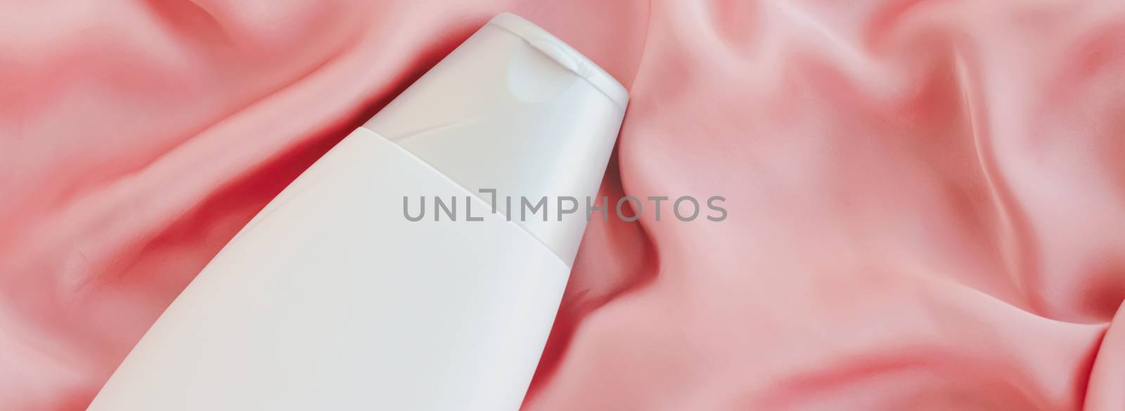 Blank label cosmetic container bottle as product mockup on pink silk background by Anneleven