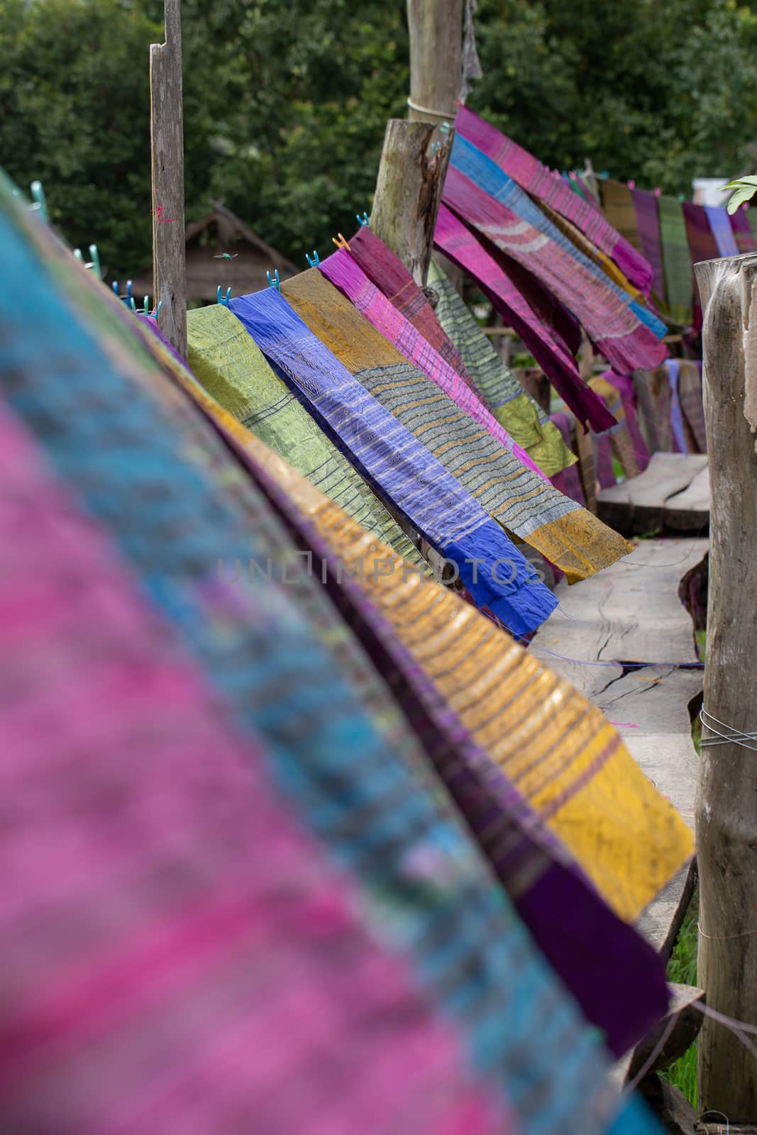 Hand woven clothes hang on wooden walkways in rice field at Sila by kaiskynet