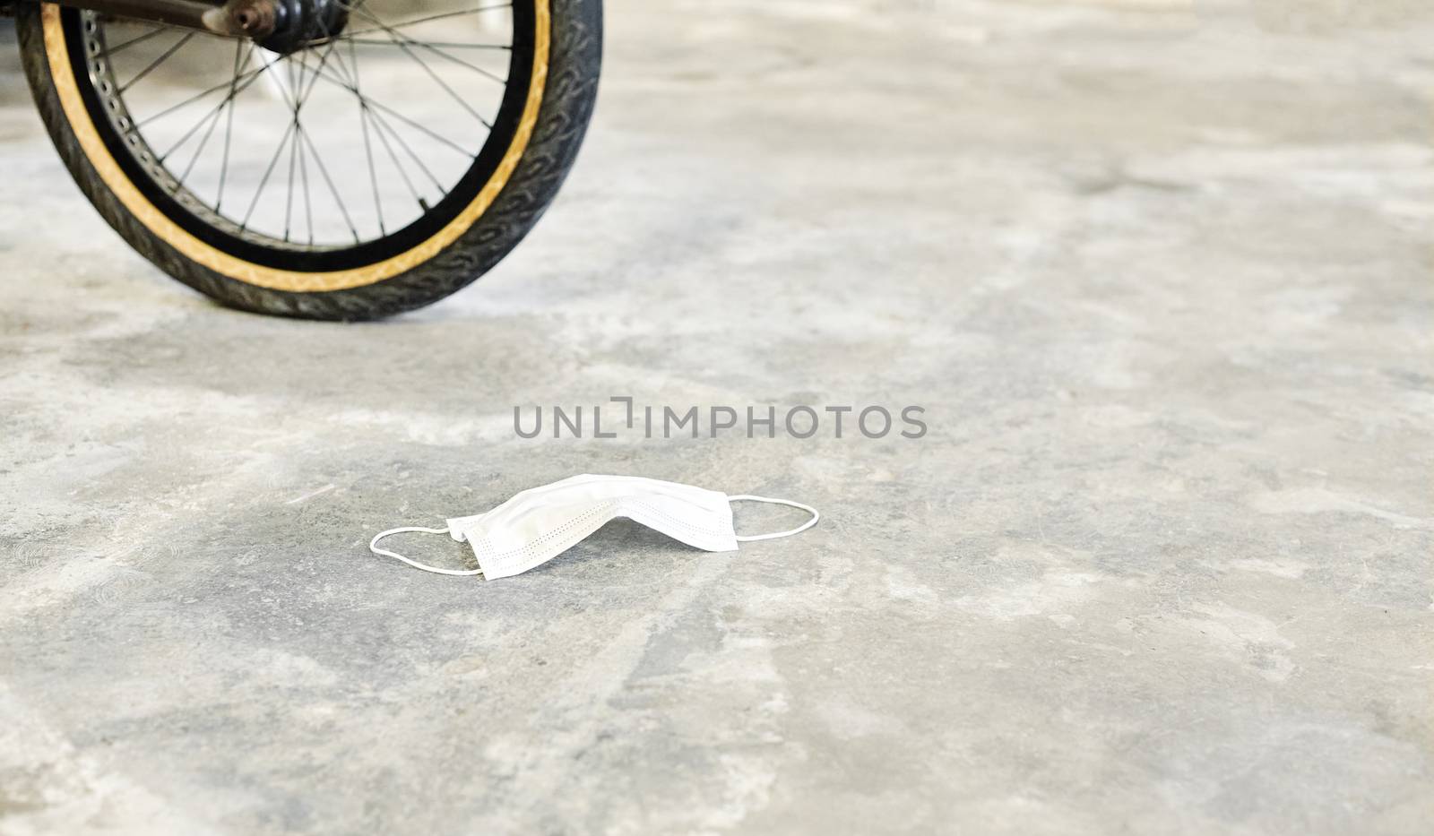 Mask lying on the ground with a bicycle wheel at the bottom in a time of new post-Coronavirus normality