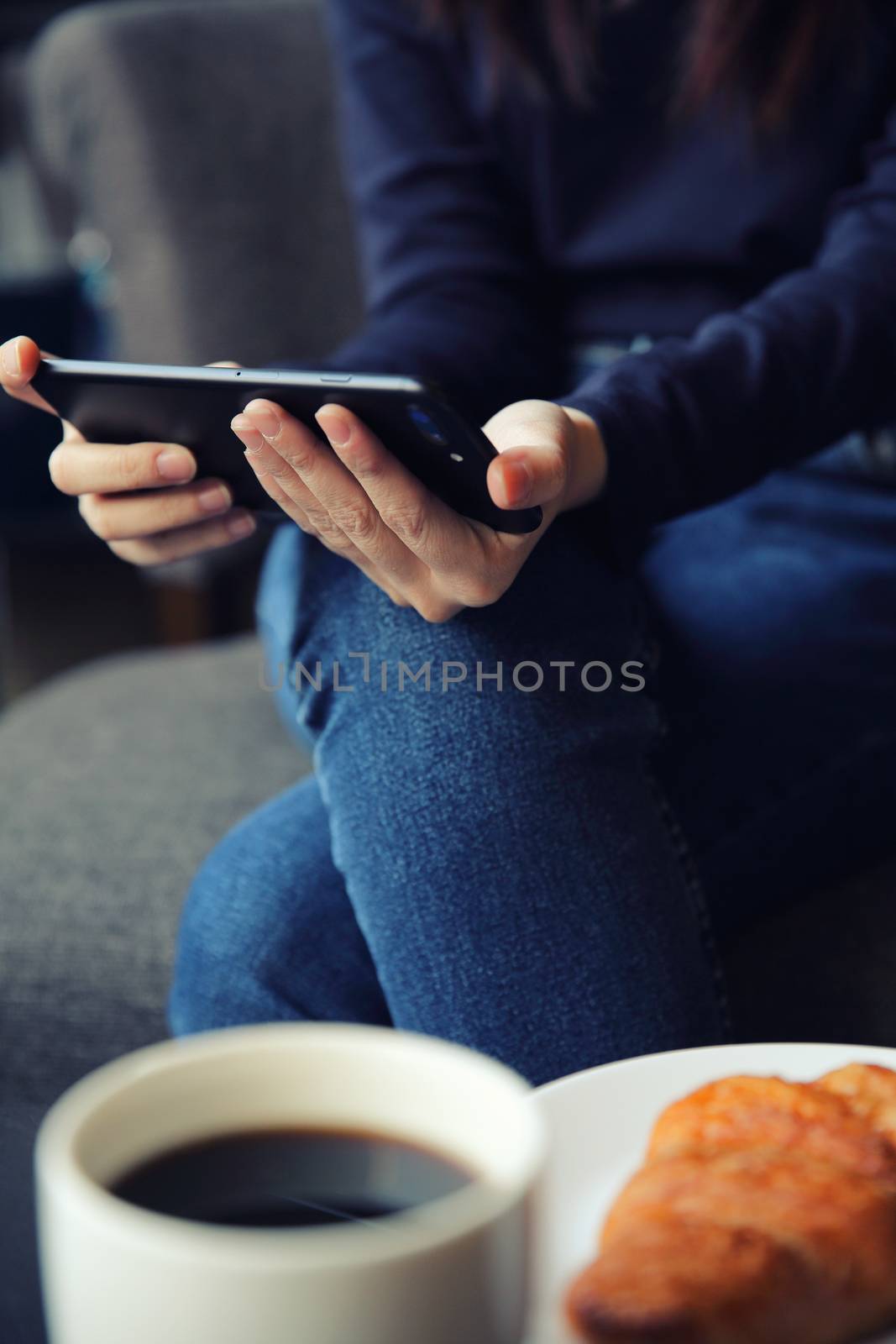 Asian female typing text message with coffe and Croissant by piyato