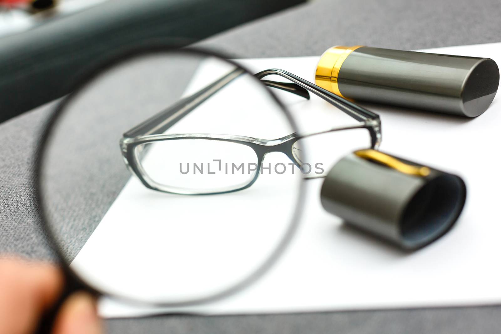 magnifier and glasses on a sheet of paper for business behind blind