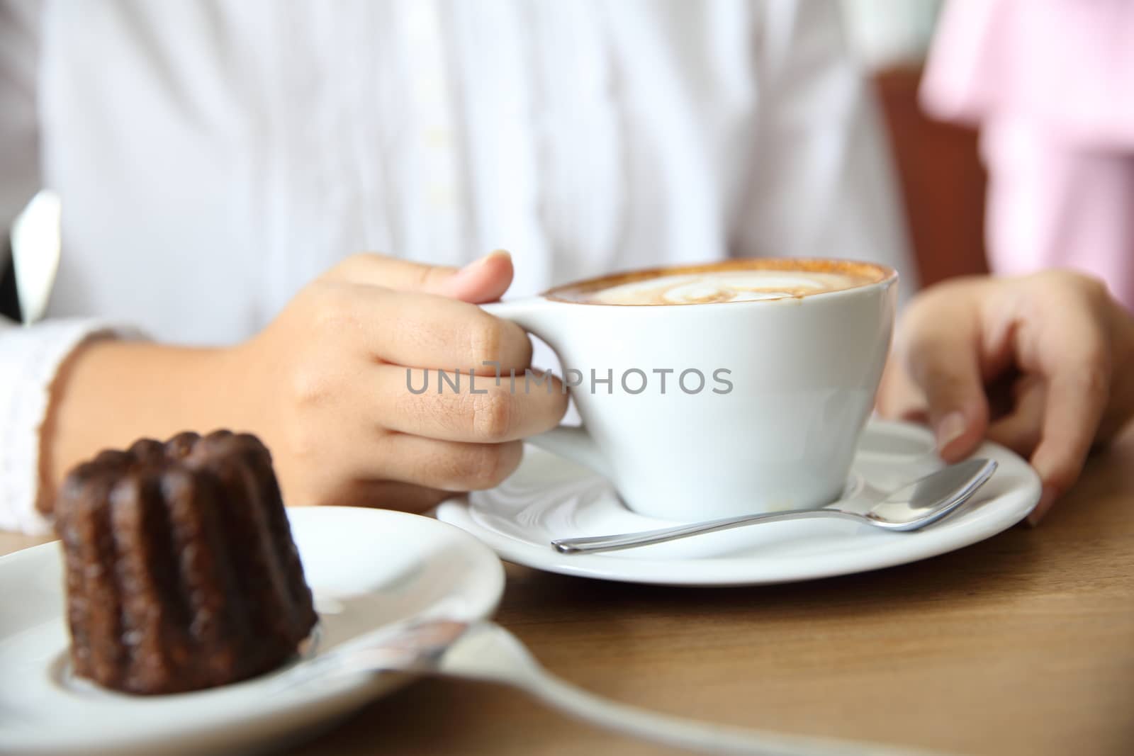 woman hands with cappuccino coffee on a wood table by piyato