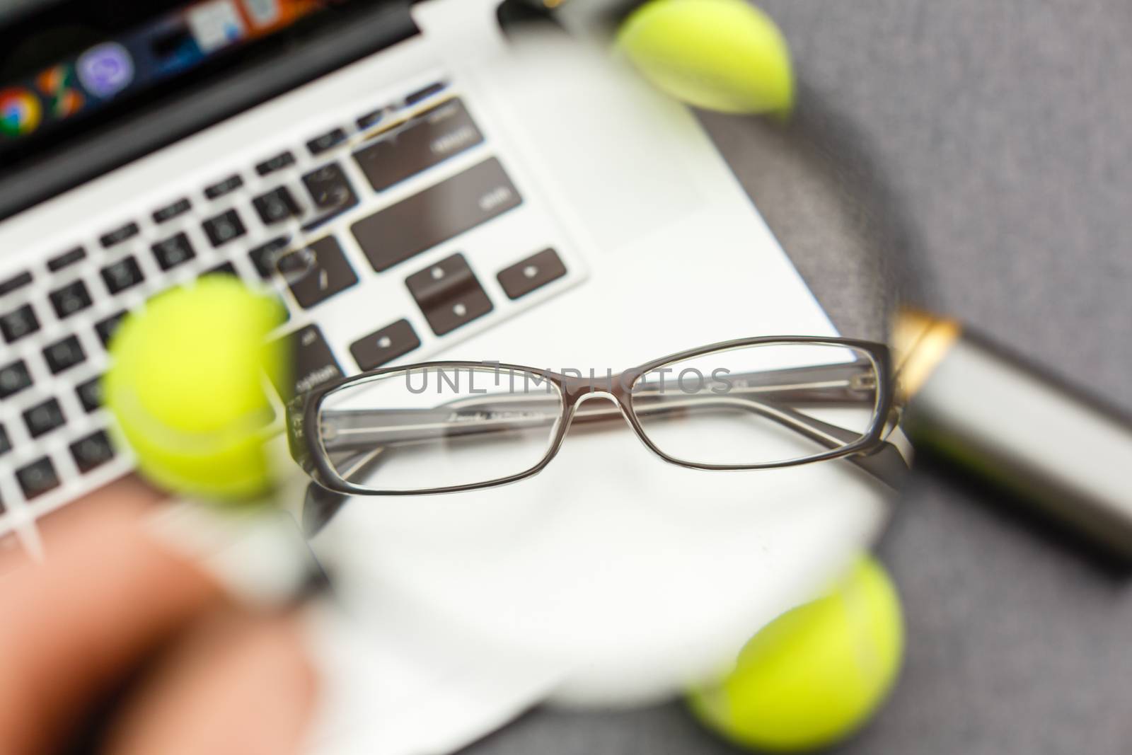 Top view of laptop, Sports Equipment, Tennis ball, Shuttlecock, glasses aon the Sports administration gray table.Business concept.