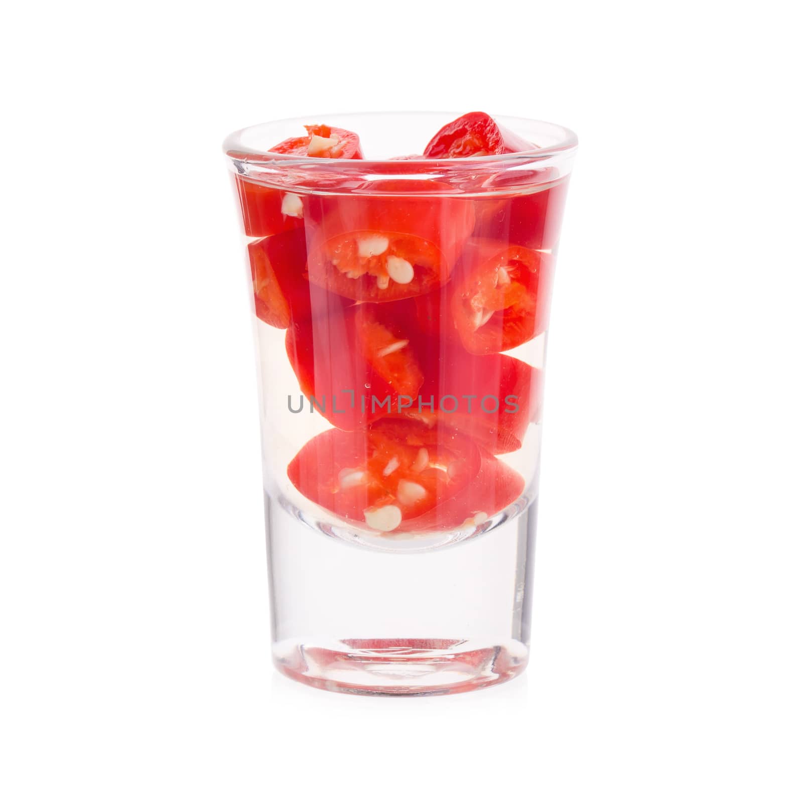 Slices of preserved red hot pepper in glass isolated on a white background.