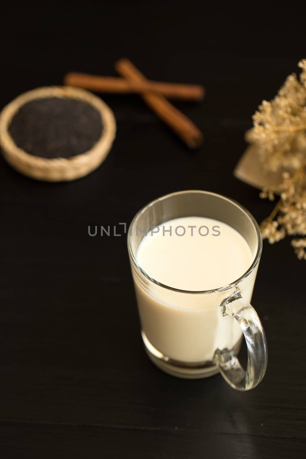 Glass of milk on black wooden background by kaiskynet