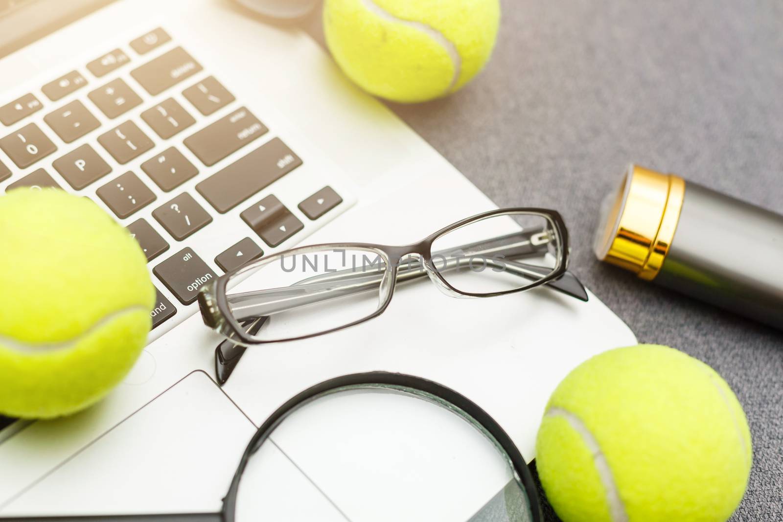 Top view of laptop, Sports Equipment, Tennis ball, Shuttlecock, glasses aon the Sports administration gray table.Business concept.