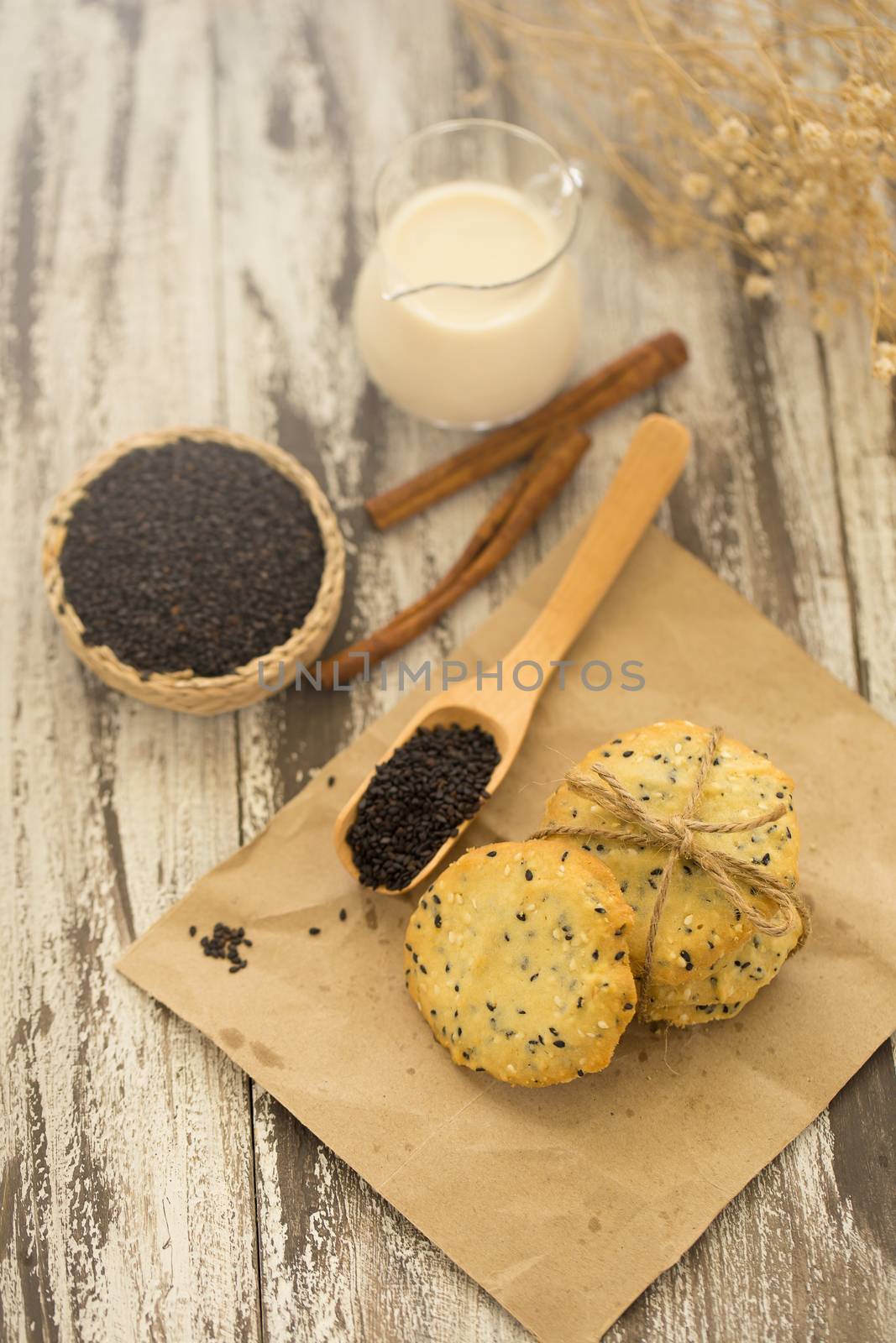 Sesame Cookies, sesame and milk on black wooden background.